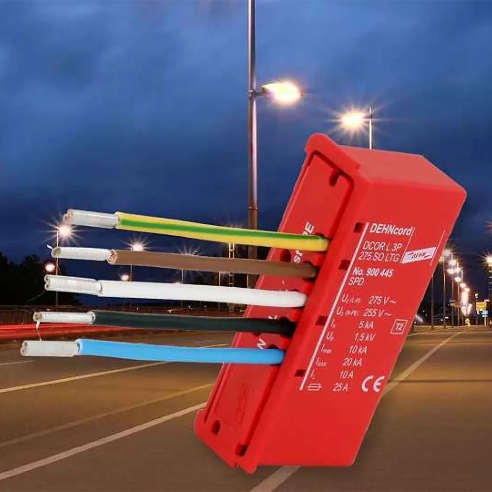 Red surge protection device with multiple colored wires connected, shown against a nighttime street with illuminated streetlights.