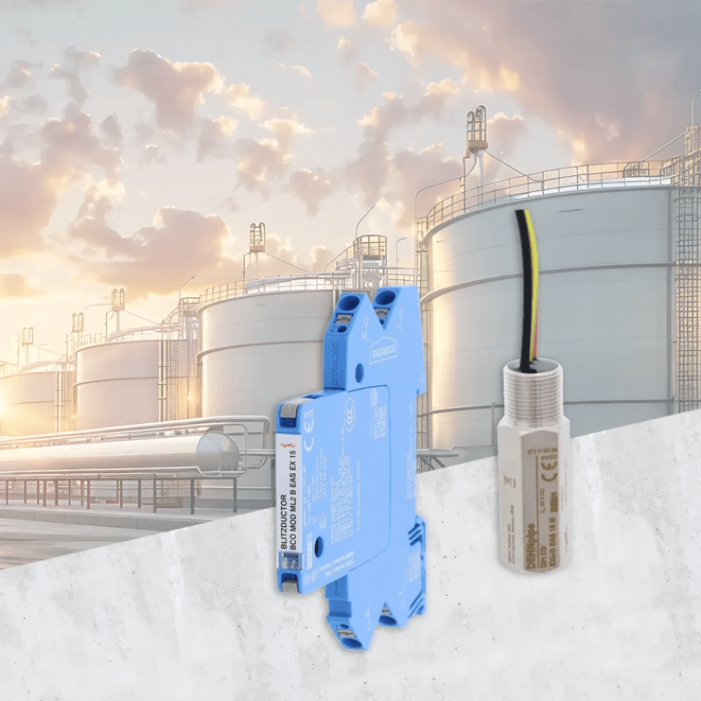 Two electronic components in front of an industrial facility with large storage tanks and a cloudy sky.