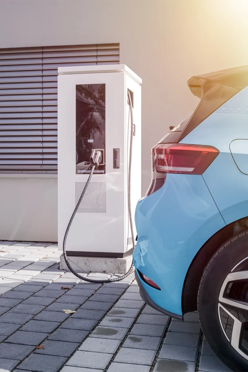 A captivating image displays a modern scene, where an electric car, its image a symbol of sustainability, parks on a contrasting brick sidewalk. The white cars sleek design and the electric charging stations dog-display window create a visually appealing fusion of convenience and eco-friendliness.