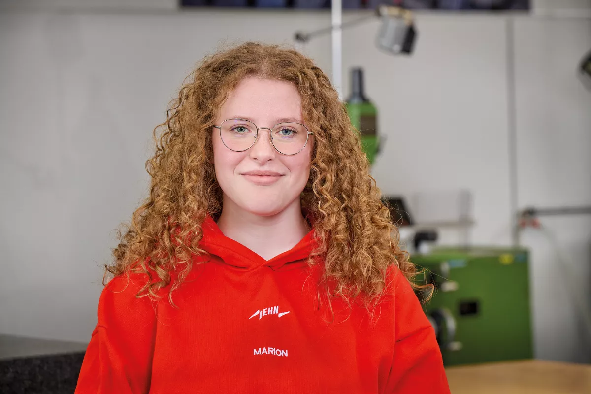 Person with curly hair wearing a red hoodie.
